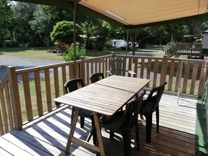 Eine Terrasse im Freien mit Tisch und Stühlen, umgeben von einem Holzgeländer.