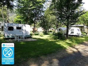 Ein Campingplatz mit Wohnmobilen, einem Picknicktisch und einem Schild, das darauf hinweist, dass keine privaten Sanitäranlagen vorhanden sind.