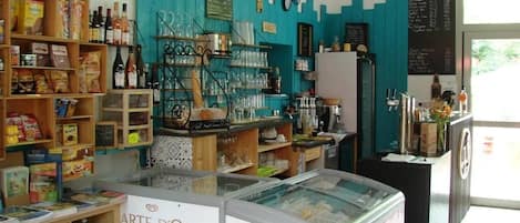 Un café avec des étagères remplies d’en-cas, un présentoir et un panneau affichant le menu.