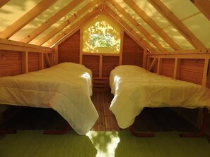 Ein kleines Schlafzimmer im Dachgeschoss mit zwei Betten, einem Fenster und Holzbalken.