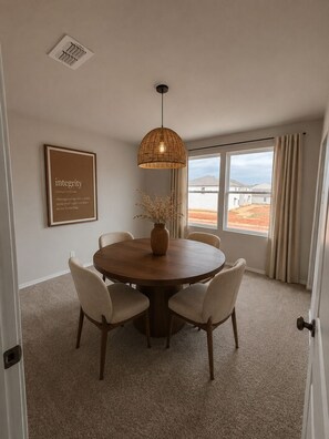 A dining area with a round table, four chairs, a hanging light fixture, a vase with dried plants, a framed quote on the wall, and a view through the window. - Spacious 5-bedroom house in quaint Abilene with High-speed Internet (Abilene)