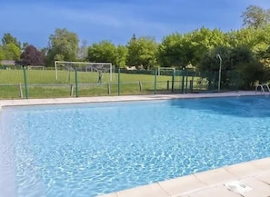 A swimming pool with a green fence, trees, and a clear sky. - ZEcamping 3* piscine pet friendly locatif 20m2 4 pers (Montaut)