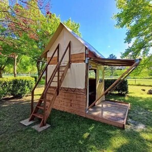 Ein kleines, eingeschossiges Holzgebäude mit Satteldach, einer Treppe, die zu einer Tür führt, und einem kleinen Vorbereich.