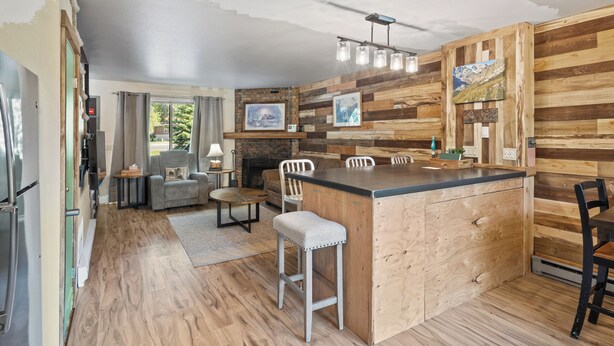 A kitchen with a wooden island, bar stools, a dining table, and chairs. - Château Rouge ~ 210 Sawmill Flats (Red Lodge)