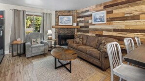 A living room with a fireplace, a sofa, a coffee table, and a dining area with chairs. - Château Rouge ~ 210 Sawmill Flats (Red Lodge)
