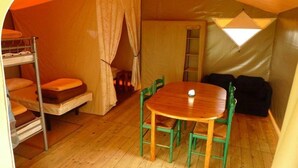 Ein Zeltraum mit Etagenbetten, einem Tisch, Stühlen und einer Leiter.
