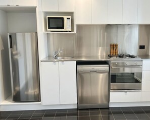 Une cuisine moderne équipée d’appareils électroménagers en acier inoxydable, d’un four à micro-ondes, d’un lave-vaisselle et d’un four.