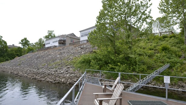 A wooden dock with chairs and a metal bench, a rocky hillside, and a building in the background. - Relaxing Resort Condo for 6 guests, In The Heart of Beautiful Branson! (Branson)