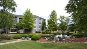 A building with a pond, green lawn, and picnic tables. - Relaxing Resort Condo for 6 guests, In The Heart of Beautiful Branson! (Branson)