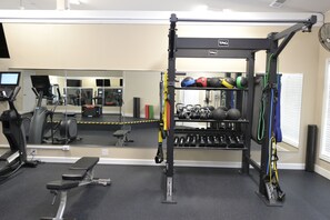 A gym with exercise equipment, a bench, and a mirror.