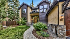 A two-story house with a stone foundation, a wooden fence, and a well-maintained garden.