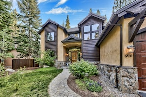 A two-story house with a stone foundation, a wooden fence, and a well-maintained garden.