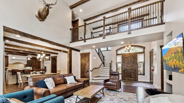 A spacious living area with a high ceiling, a staircase, and a dining area.