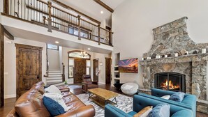 A spacious living room with a stone fireplace, leather sofas, and a wooden coffee table.