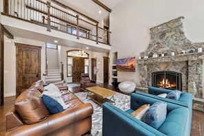 A spacious living room with a stone fireplace, leather sofas, and a wooden coffee table.