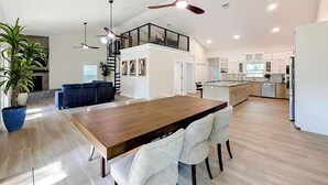 A spacious living area with a wooden dining table, white chairs, a blue potted plant, and a ceiling fan. - Rainbow River Oasis With Private Dock (Dunnellon)
