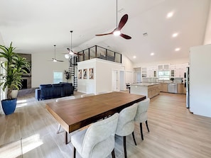 A spacious living area with a wooden dining table, white chairs, a blue potted plant, and a ceiling fan. - Rainbow River Oasis With Private Dock (Dunnellon)