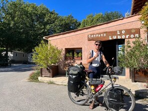 Ein Gebäude mit einem Schild, auf dem 'Camping Le Luberon' steht, und eine Person, die neben einem Fahrrad steht.