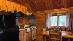 A wooden cabin kitchen with a refrigerator, stove, and wooden cabinets.