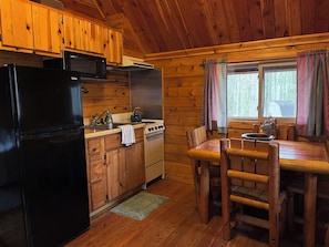 A wooden cabin kitchen with a refrigerator, stove, and wooden cabinets.