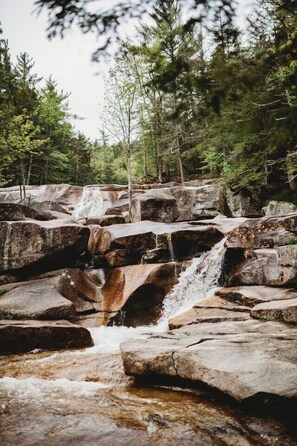 Eine natürliche Felslandschaft mit Wasserfall und dichtem Wald.