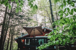 Eine Hütte mit einem großen Sonnenschirm, umgeben von Bäumen.