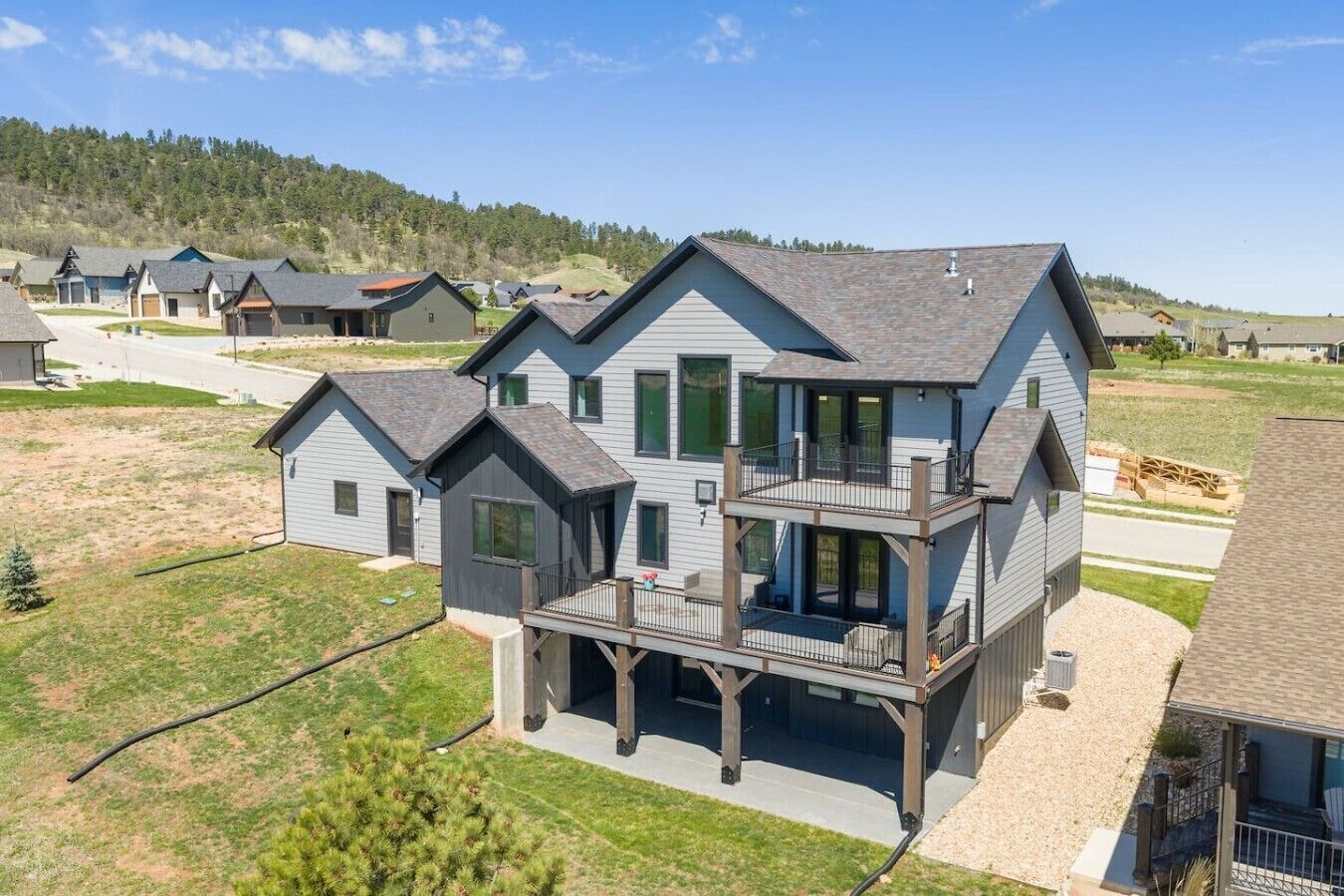 A two-story house with a balcony, a driveway, and a grassy yard.