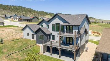 A two-story house with a balcony, a driveway, and a grassy yard.