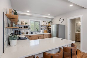 Une cuisine moderne dotée d’un îlot central, de meubles en bois et d’un réfrigérateur encastré.