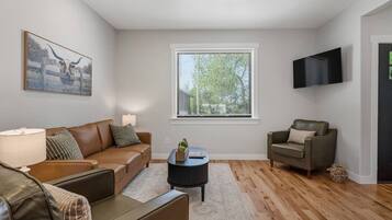 A living room with a brown leather sofa, a smaller sofa, a coffee table, and a TV mounted on the wall.