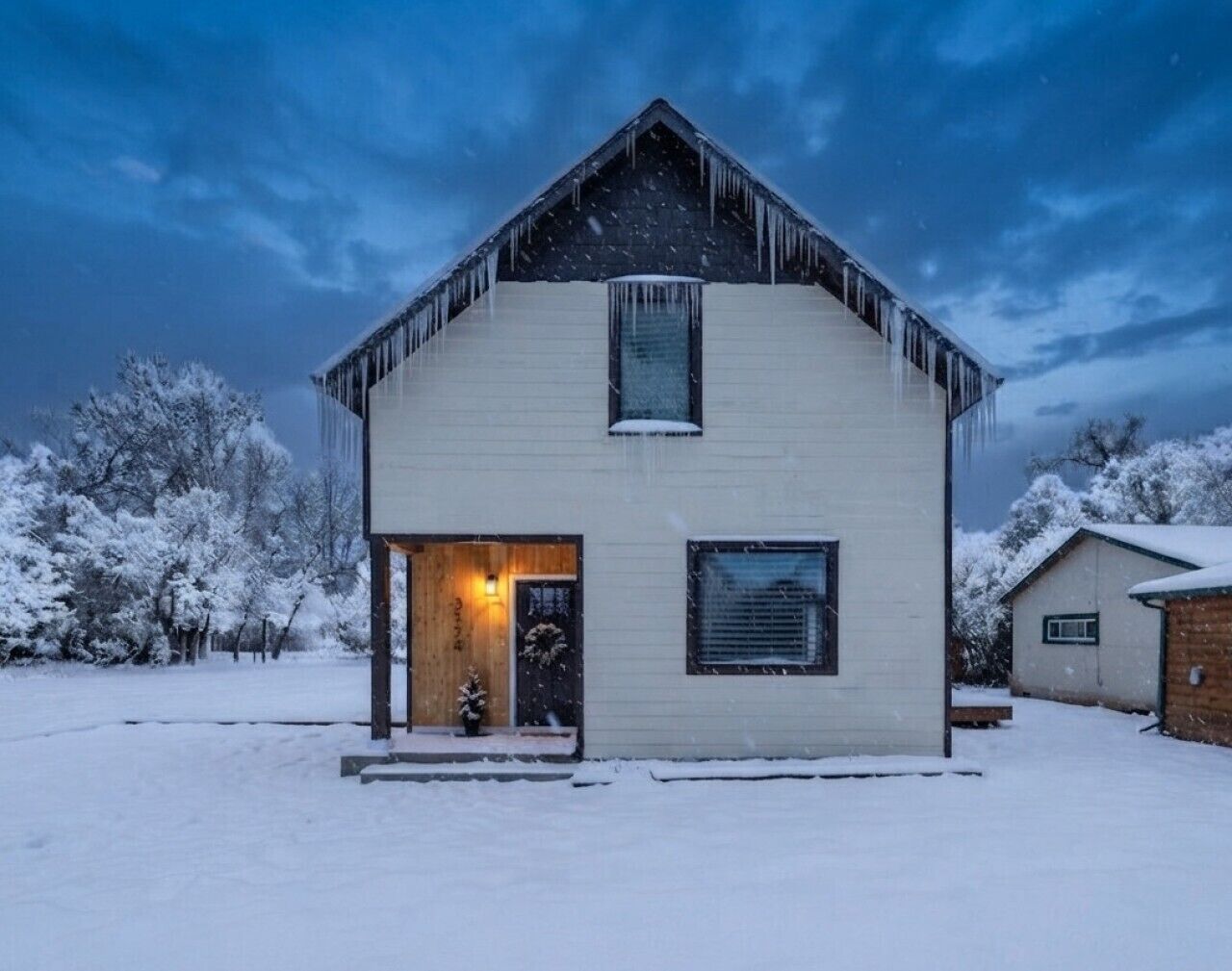 Une maison à deux étages avec un toit en pente, une porte d’entrée et un petit porche.
