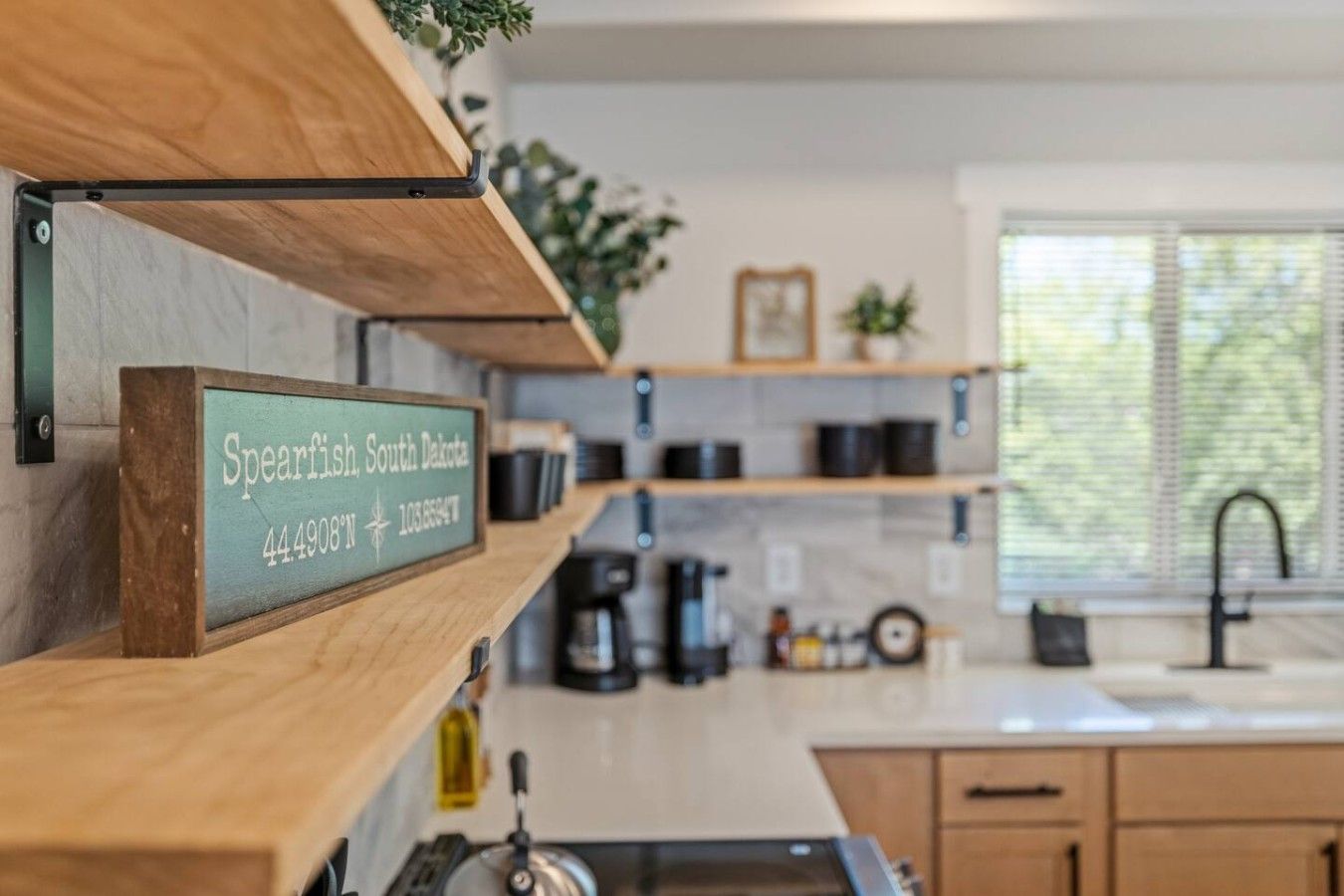 Une cuisine avec des étagères en bois, une machine à café et un panneau indiquant que l’on se trouve à Spearfish, dans le Dakota du Sud.