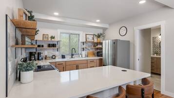 A modern kitchen with a central island, wooden cabinets, and a built-in refrigerator.