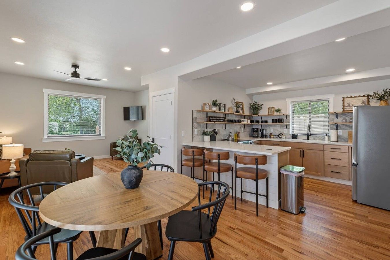 A modern kitchen with a central island, bar stools, and a dining table with chairs.