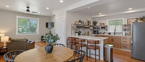 Una cocina moderna con una isla central, taburetes de bar y una mesa de comedor con sillas.
