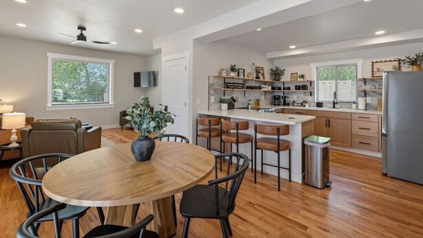 Una cocina moderna con una isla central, suelo de madera y un comedor con una mesa redonda y sillas.