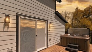 Una terraza con jacuzzi, puerta corrediza de vidrio y luces empotradas.