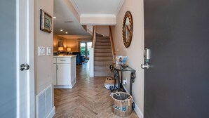 A hallway with a staircase leading to a kitchen area, a door with a handle, and a wall-mounted mirror. - Oceanfront Complex - New Rental
- Steps to Beach/Pool/Coligny 
- Sleeps 6pp (Hilton Head Island)