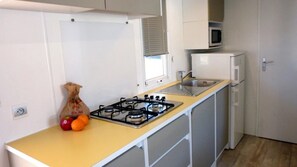 A compact kitchen with a gas stove, sink, microwave, and a small refrigerator. - Camping 3 étoiles - ccbcbig (Hyères)