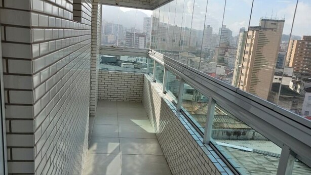A narrow balcony with tiled walls and a glass railing, overlooking a cityscape. - Family Apartment with 2 Bedrooms in the City Center, 200m from the Beach, Furnished and with AC (Praia Grande)