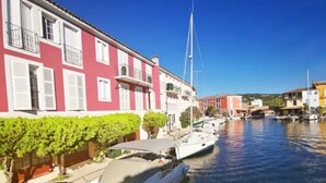 Een gracht met bootjes, een rood gebouw met witte luiken en een helderblauwe lucht.