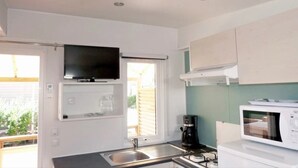 Een compacte keuken met een ingebouwde televisie, een koffiezetapparaat en een magnetron.