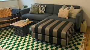 Ein Wohnzimmer mit einer Couch, einem Couchtisch, einem gemusterten Teppich und einer Wand mit gerahmten Bildern.