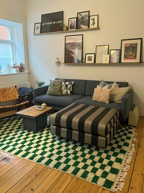 Ein Wohnzimmer mit einer Couch, einem Couchtisch, einem gemusterten Teppich und einer Wand mit gerahmten Bildern.