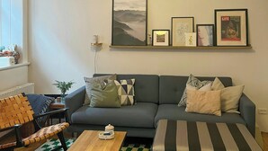 Ein Wohnzimmer mit einer Couch, einem Couchtisch, einem gemusterten Teppich und Wandbildern.