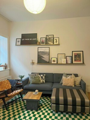 Ein Wohnzimmer mit einer Couch, einem Couchtisch, einem gemusterten Teppich und Wandbildern.