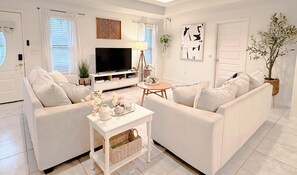 A living room with a white sofa, a coffee table, a TV, and a potted plant. - Bentsen Palm Getaway • 4 Beds • Fast WiFi • Close to Shops (Mission)