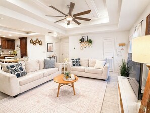 Ein Wohnzimmer mit zwei Sofas, einem Couchtisch, einem Deckenventilator und einem Fernseher.