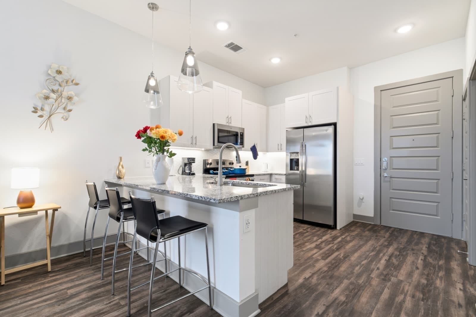 A modern kitchen with white cabinets, stainless steel appliances, and a central island with bar stools.