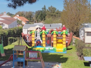 An inflatable play structure with a pirate theme, surrounded by a grassy area and residential buildings. - Camping 3 étoiles - Piscine  - ccbfidh (Les Moutiers-en-Retz)